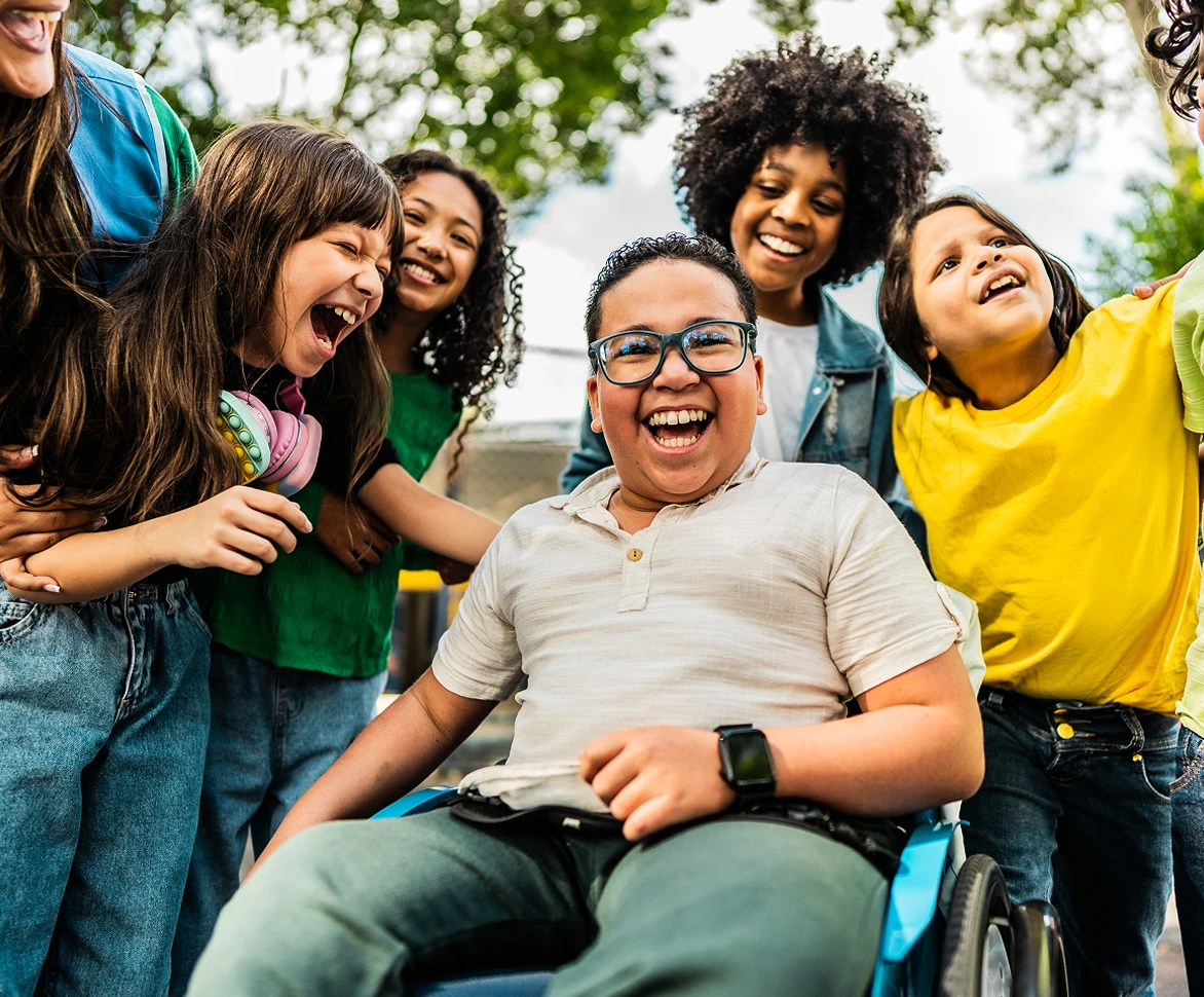 Child in wheelchair with happy kids around him