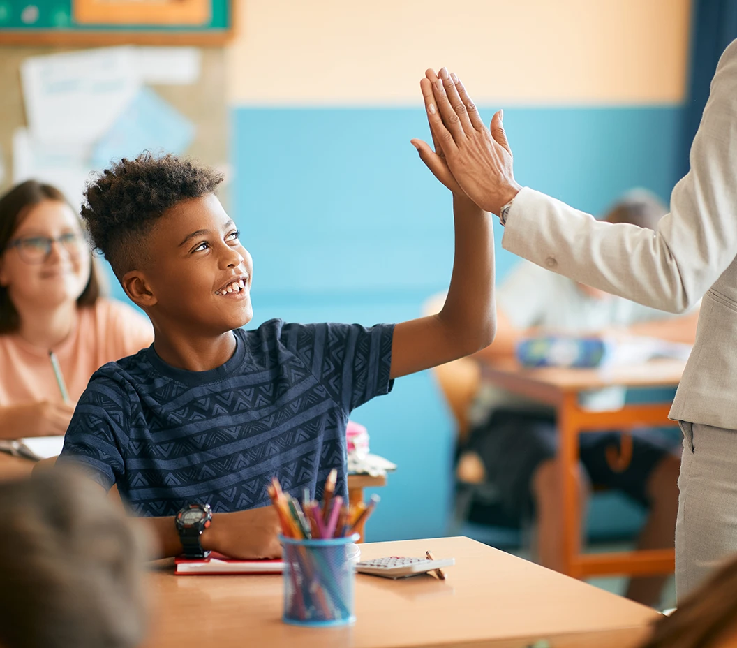 Happy African American schoolboy giving high-five to his teacher